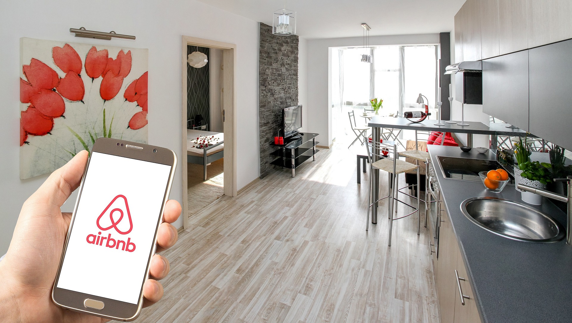 Main tenant un téléphone avec le logo Airbnb sur l'écran, dans un appartement